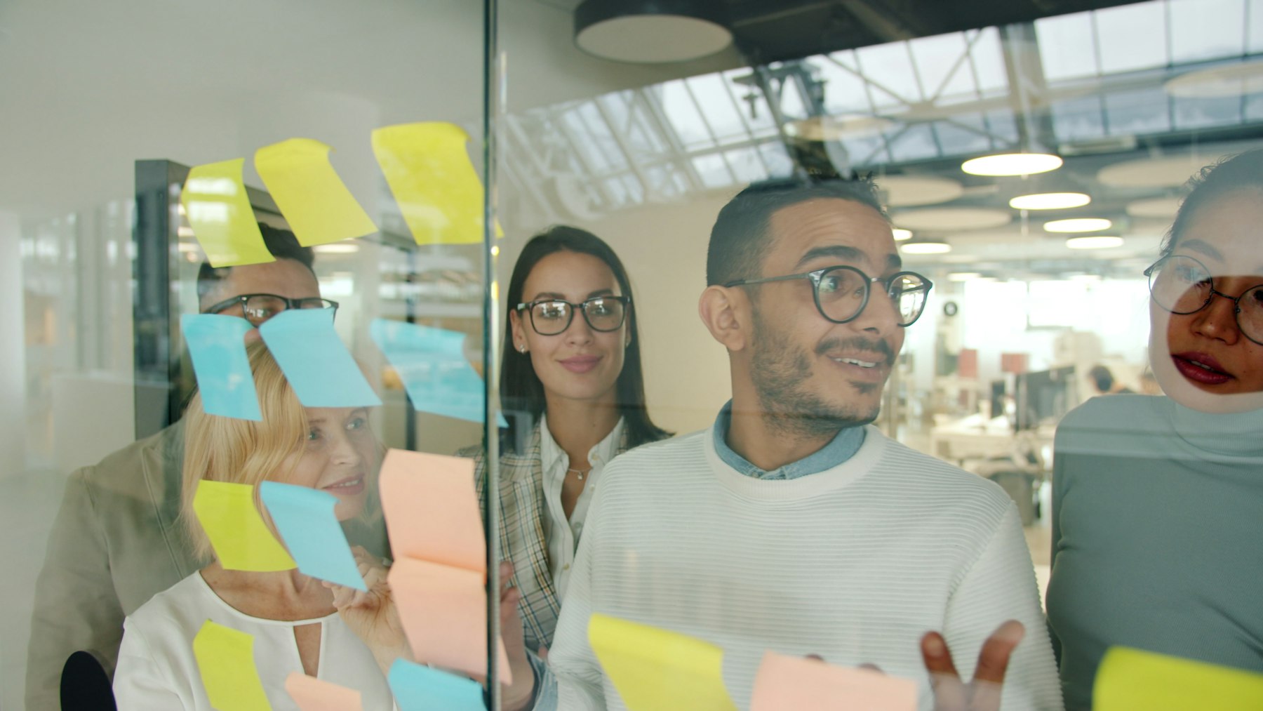 Creative team brainstorming with sticky notes on a glass wall during a brand workshop