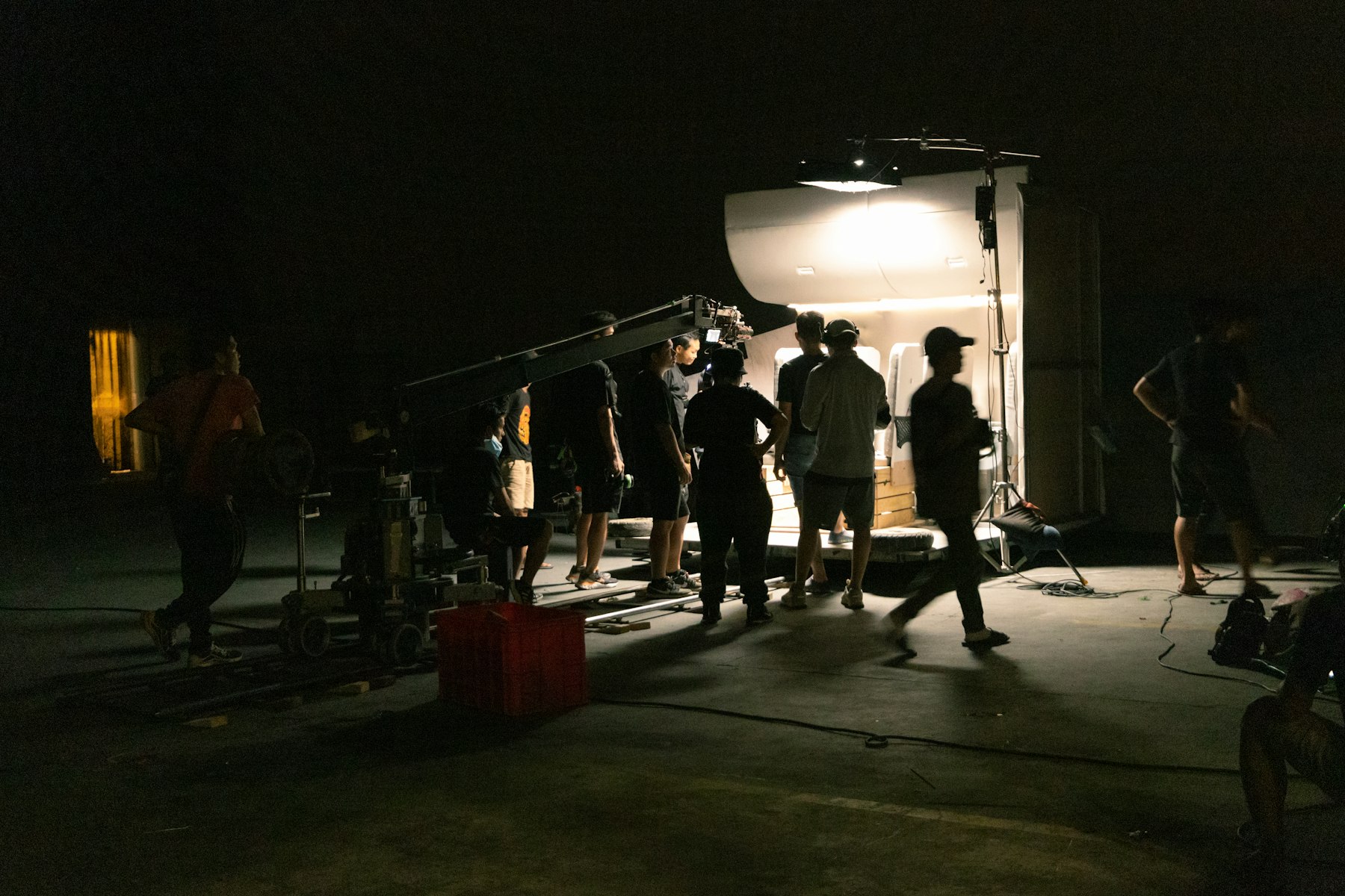 Production crew gathered around a camera setup in a dark studio environment